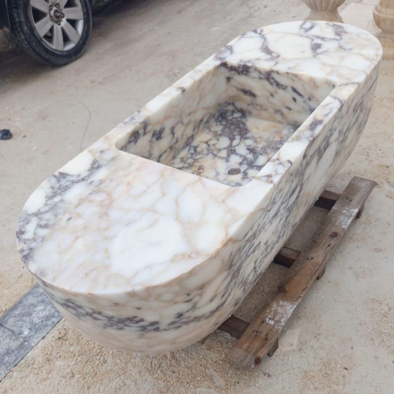 Collectible architectural marble sink made from rare Calacatta Viola marble, suspended luxury bathroom basin carved by hand from a massive stone block, floating vanity sink with dramatic sculptural presence designed for luxury villas and penthouses, premium handmade marble sink by MarbleSinkCo masters shipped worldwide with DHL Express