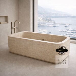May include: A rectangular beige stone bathtub with rounded edges. The tub is in a modern bathroom with a large window overlooking a harbor. The image includes a faucet and the text "ORIGINAL PRODUCT HIGH QUALITY".
