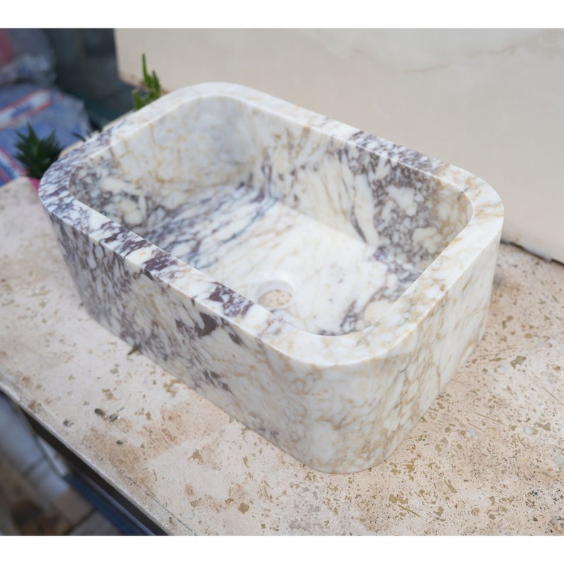 Luxury handcrafted Calacatta Viola marble floating wall mounted bathroom sink with fluted front in a premium designer bathroom.