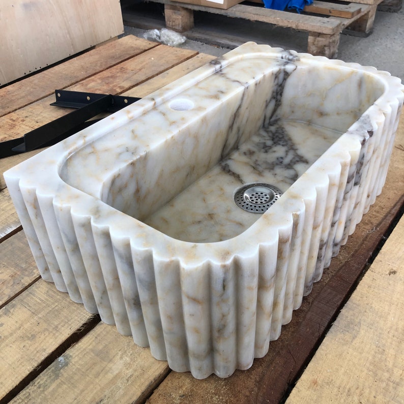 calacatta viola marble sink, fluted marble sink, grooved marble sink, wall mounted marble sink, wall hung stone basin, small powder room sink, compact bathroom sink, luxury powder room vanity, handcrafted marble basin, natural stone bathroom sink, custom marble sink, purple marble sink, burgundy marble sink, floating marble vanity, designer bathroom sink, boutique hotel bathroom sink, narrow bathroom sink, handmade stone sink, marble washbasin, architectural bathroom sink