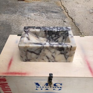 Calacatta Viola marble wall-mount sink with stunning natural veining. Handcrafted floating stone basin with no overflow, single faucet hole. Perfect for luxury bathrooms, interior designers, boutique hotels, and modern renovations. Ideal as a vessel sink, bar sink, or designer washbasin. Unique Italian marble sink for minimalist, high-end bathrooms. Trending marble bathroom decor, handcrafted stone sink.