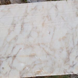 May include: A close-up of a white marble slab with brown veining. The marble has a smooth, polished surface.