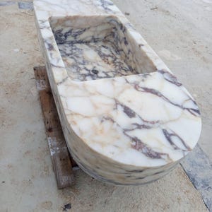 Luxury floating marble sink handcrafted from rare Calacatta Viola marble, suspended bathroom vanity basin designed for villas, penthouses and luxury homes, sculptural stone sink carved from a 2 ton marble block, architectural designer sink suspended with steel chains creating a stunning centerpiece for modern luxury bathrooms
