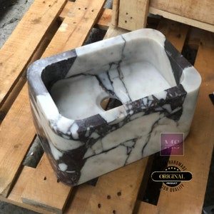 Front view of the handmade marble bathroom sink, highlighting its thick stone body, rounded edges and bold burgundy veining.