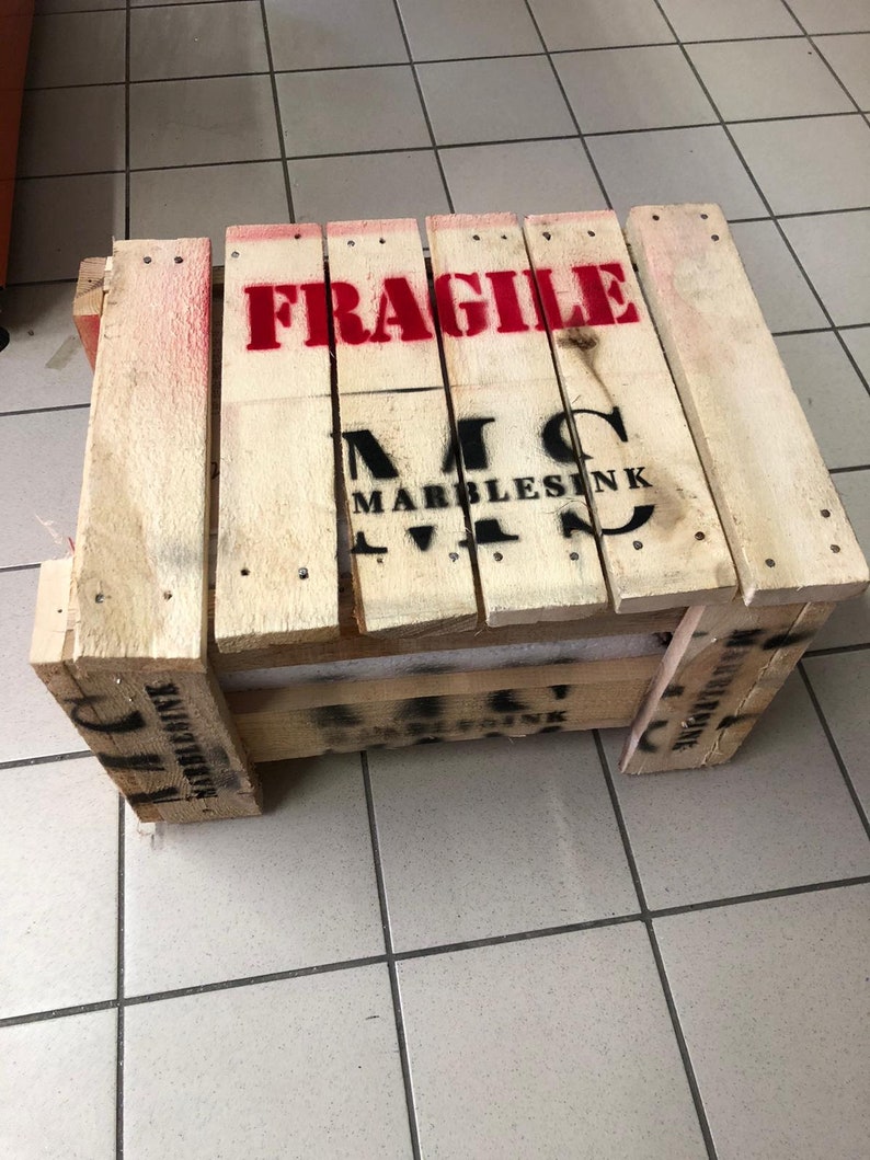 May include: A wooden crate with the word "FRAGILE" printed in red letters. The crate is labeled with the text "MARBLESINK" in black letters.