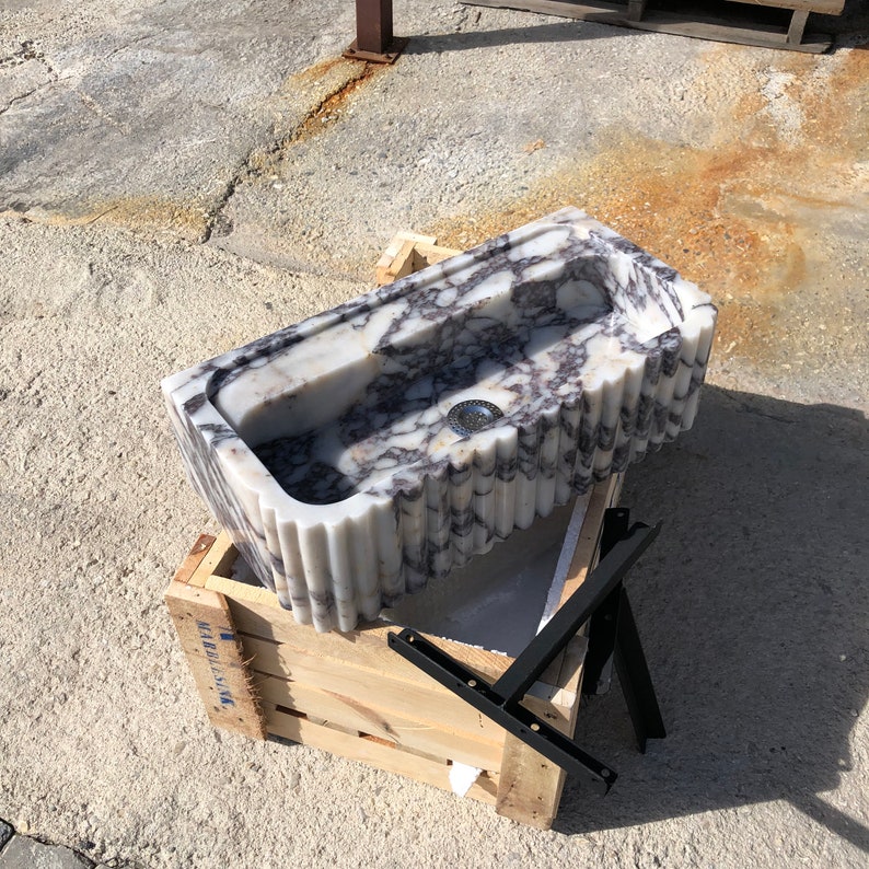 Rear view of the Calacatta Viola wall-mounted basin showing the solid marble back, carved profile and mounting area.