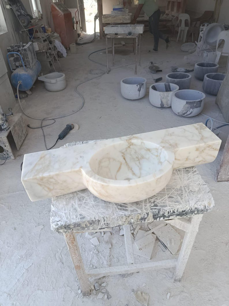 Luxurious wall-mounted Calacatta marble sink carved from a single block. Featuring 3 faucet holes, fluted front design, and floating vanity look. Ideal for modern, minimalist bathrooms. Custom sizes available. Handmade from natural Italian stone. Bathroom sink, marble vanity, stone basin, designer sink, fluted marble, wall mount sink, handmade sink, rectangular sink, luxury bathroom decor.