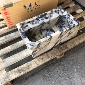 Stone artisan carving a Calacatta Viola marble sink in the workshop
