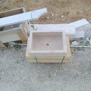 Luxury handcrafted natural travertine wall mounted bathroom sink installed in a premium modern bathroom with chrome fixtures.