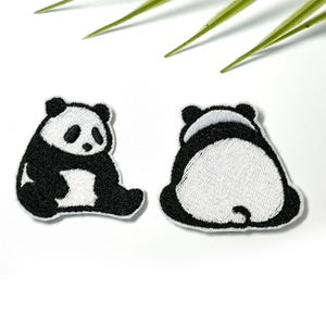 May include: Two embroidered patches featuring a panda bear. The left patch shows a seated panda facing forward with black and white thread. The right patch shows the back view of a seated panda with a white circular center and black edges.