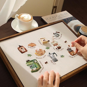 Könnte beinhalten: Ein Set aus drei Keramikbechern mit gesprenkelter, matter Oberfläche. Die Becher sind in Creme-, Hellgrau- und Dunkelgrautönen gehalten. Jeder Becher hat ein schlichtes, minimalistisches Design, ideal für Kaffee oder Tee.