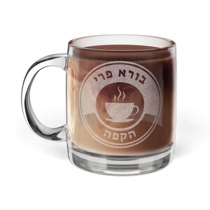 May include: A clear glass coffee mug with a handle, filled with a layered coffee drink. The mug features a circular design with text and a coffee cup graphic. The coffee drink has a gradient of colours, from light brown to dark brown.