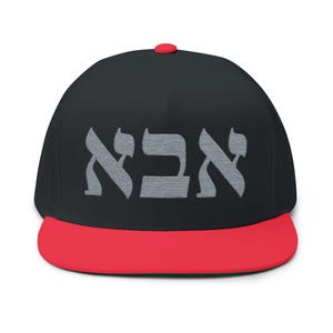 May include: A black flat-brimmed baseball cap with a red peak and a red button. The cap has the Hebrew word "אבא" embroidered in grey.