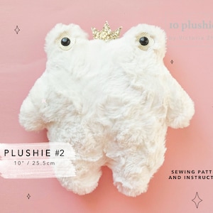 May include: White plush frog with a gold crown and black eyes. The frog is 10 inches tall and is a sewing pattern for a plush toy.
