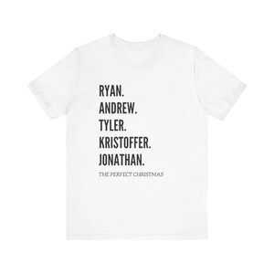 May include: White t-shirt with black text. The text lists five names: Ryan, Andrew, Tyler, Kristoffer, and Jonathan. Below the names is the phrase "THE PERFECT CHRISTMAS".