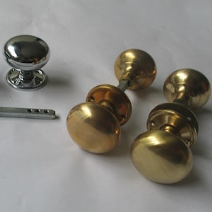 Peut inclure: Ensemble de quincaillerie de porte, comprenant deux poignées de porte chromées brillantes, une barre de connexion métallique et trois paires de poignées de porte en laiton. Les boutons sont ronds.