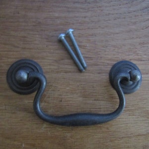 May include: Black metal drawer pull with a rounded, decorative top and a curved handle. Two silver screws are included.