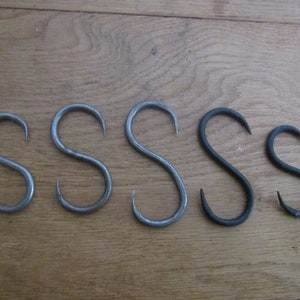 May include: Five metal S-shaped hooks in different sizes. The hooks are made of metal and have a silver and black finish.