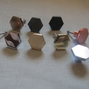 May include: Assortment of hexagonal cabinet knobs in various finishes, including black, silver, gold, and copper.