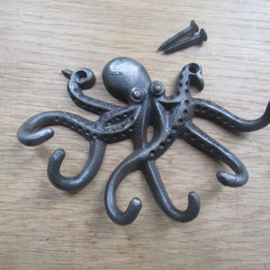 May include: A cast iron octopus wall hook with eight tentacles, each ending in a hook. The octopus is painted in a dark gray color.