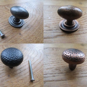 Könnte beinhalten: Vier verschiedene Schrankknöpfe mit Schrauben werden gezeigt. Die Knöpfe haben unterschiedliche Formen und Oberflächen, darunter ein Oval, eine gehämmerten schwarzen Kugel und eine kupferfarbene Pilzform. Die Hardware ist für Möbel und Heimdekoration konzipiert.