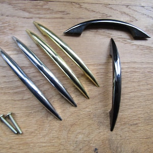 Puede incluir: Surtido de herrajes para armarios, incluyendo cuatro tiradores de cajones plateados y dos dorados, y dos pomos de armario negros.