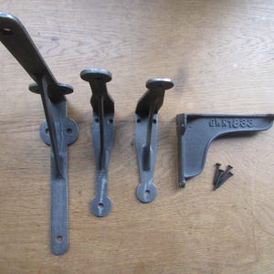 Puede incluir: Un juego de cuatro escuadras de estantería de hierro fundido gris oscuro, de varias formas y tamaños. Una escuadra está marcada con "GWR1888". Incluye tornillos. Ideal para decoración rústica o industrial. Medidas en centímetros.