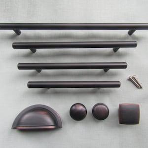 May include: A selection of dark bronze cabinet hardware, featuring bar pulls of varying lengths, a cup pull, round knobs, and a square knob. The set includes screws, offering a comprehensive solution for kitchen or bathroom upgrades.