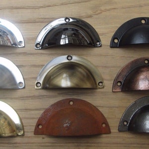 Puede incluir: Surtido de diez tiradores para puertas de armario en varios acabados, incluyendo níquel pulido, negro, latón, cobre y bronce envejecido. Los tiradores son todos de forma semicircular y tienen un diseño tradicional.