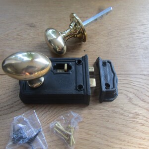 Peut inclure: Un ensemble de boutons de porte ovales en laiton avec un loquet en fonte noire. Le loquet est en deux parties et les boutons sont fixés à une broche argentée. L'ensemble comprend des vis pour l'installation.