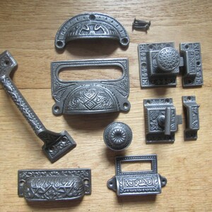 May include: A set of ten antique-style cast iron drawer pulls and cabinet hardware in a silver finish. The set includes a variety of styles, including a pull with a long handle, a knob, and a small pull with a decorative design.