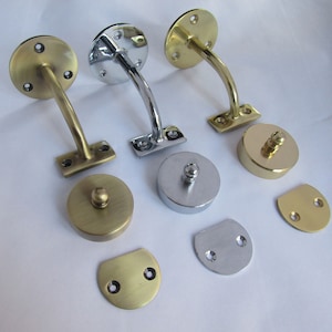 May include: Three metal handrail brackets in polished brass and chrome finishes. The brackets are curved and have a decorative ball finial. The image also shows various mounting plates and decorative caps.