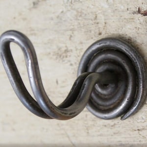 May include: A silver metal hook with a spiral base. The hook is curved and has a smooth finish.
