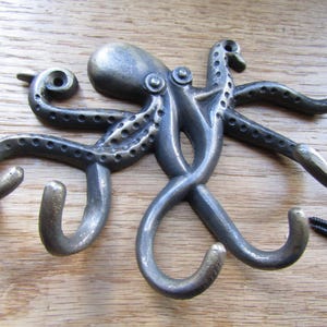 May include: A metal octopus wall hook with five hooks. The octopus is in a distressed bronze finish. The hooks are in the shape of the octopus's tentacles.