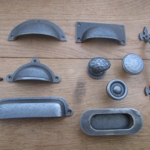 May include: A collection of eight antique-style cabinet hardware pieces in a silver finish. The hardware includes pulls, knobs, and a handle.