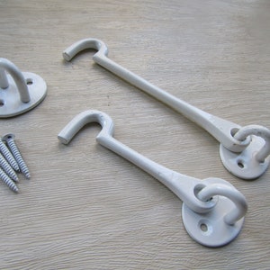 May include: Two white metal hook and eye gate latches with a round base and screws.