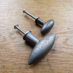 Puede incluir: Dos pomos de armario ovalados plateados con acabado texturizado. El pomo más grande mide 10 cm de largo y el pomo más pequeño mide 6,5 cm de largo.