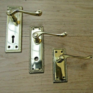 Peut inclure: Trois poignées de porte en laiton poli avec une bordure en forme de corde. Les poignées ont un style traditionnel avec un levier incurvé.