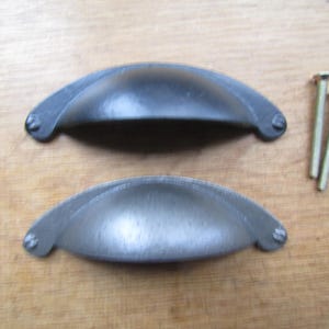 May include: Two black metal cabinet pulls with a curved, rounded shape. The pulls are shown with two screws.