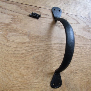 May include: Black metal door handle with a curved design and two holes for mounting screws.