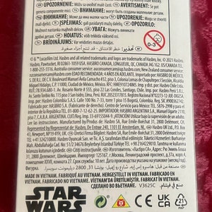 Puede incluir: Caja de producto para un juguete de Star Wars, con el logotipo de Star Wars en blanco y negro. La caja tiene varias advertencias e informaci&oacute;n reglamentaria, incluyendo un logotipo de Disney y el logotipo de Hasbro.