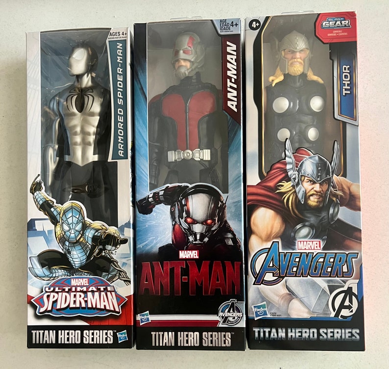 Pu&ograve; includere: Tre scatole di action figure con personaggi Marvel. Le scatole presentano "ARMORED SPIDER-MAN", "ANT-MAN" e "THOR". Ogni personaggio fa parte della "TITAN HERO SERIES" ed &egrave; consigliato per bambini dai 4 anni in su. Il logo "AVENGERS" &egrave; visibile.