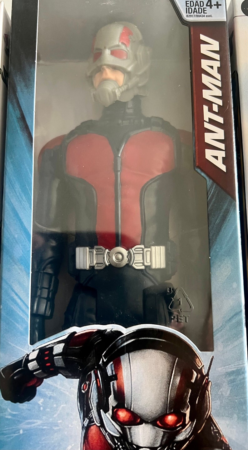 Pu&ograve; includere: Action figure di Ant-Man in una confezione di plastica trasparente. La figura indossa un costume rosso e nero con una cintura argentata. La confezione include il testo "ANT-MAN" e "EDAD 4+".