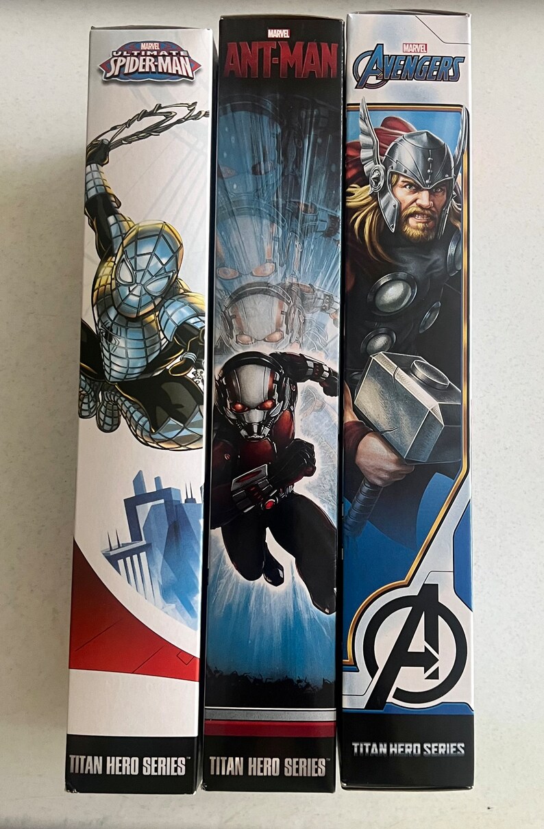 Pu&ograve; includere: Tre scatole di action figure della serie Titan Hero con personaggi Marvel. Le scatole mostrano Spider-Man, Ant-Man e Thor degli Avengers. Ogni scatola ha una diversa combinazione di colori e illustrazione del personaggio.