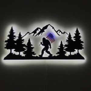 Big Foot con bandiera USA, decorazione da parete in metallo naturale, Big Foot illuminato a LED nella foresta, decorazione della fauna selvatica, ventilatori Big Foot, decorazione della caverna dell'uomo, decorazione del garage