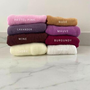 May include: A stack of eight fabric squares in different colors, including pastel pink, lavender, wine, ivory, white, burgundy, mauve, and nude. The fabric squares are arranged from lightest to darkest.