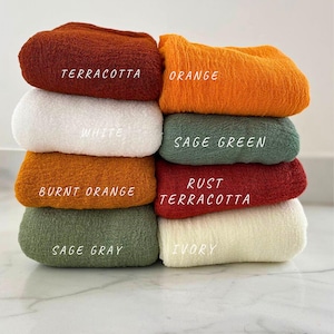 Può includere: Un mucchio di otto campioni di tessuto in vari colori, tra cui terracotta, arancione, bianco, verde salvia, arancione bruciato, terracotta ruggine, grigio salvia e avorio.