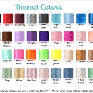 May include: A color chart displaying rows of embroidery thread spools in various shades including white, ivory, black, red, burgundy, grey, blue, yellow, pink, green, orange, and brown, with each color labeled by name below the spool.