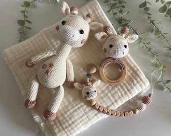 May include: A cream-colored muslin blanket with a crocheted giraffe toy, a wooden giraffe teether, and a wooden bead necklace with the name "Alexander" spelled out.