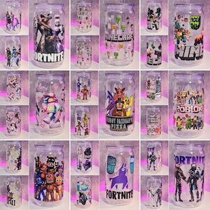 May include: A collection of 18 clear plastic tumblers with various video game character designs. The designs include Fortnite, Minecraft, Roblox, and Five Nights at Freddy's.